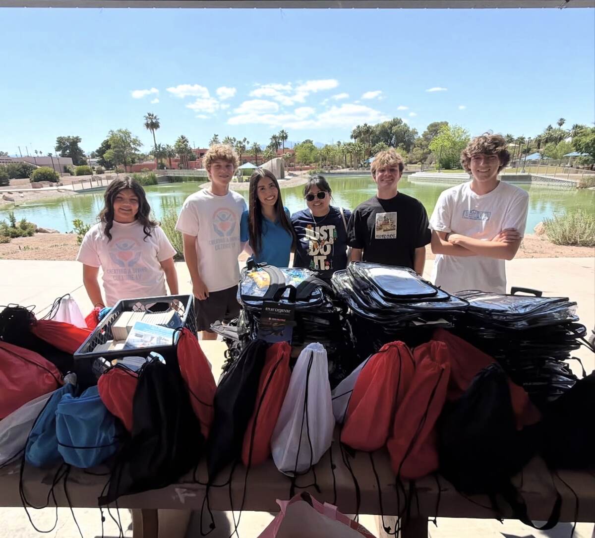 Youth volunteers standing behind backpacks and outreach supply bags